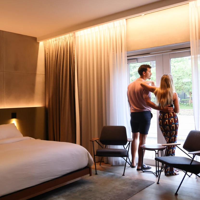 a couple standing facing a window in a hotel bedroom