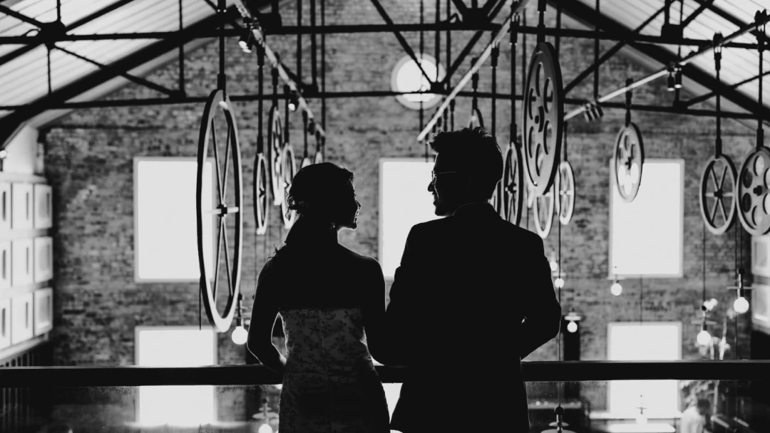 black and white picture of a couple standing on a balcony in a large hall