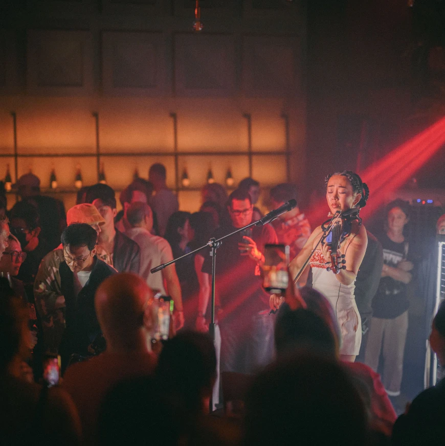 female violinist playing a violin on stage with a large crowd surrounding her