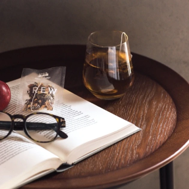 partners-amuse-1 a cup of tea on a wooden table next to an opened book