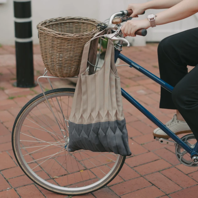 partners-ginlee-1 a person riding a bicycle with a basket and tote bag hanging from the side