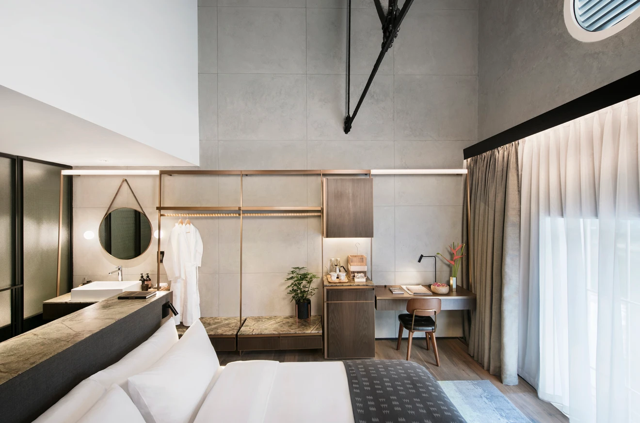 hotel bedroom with king sized bed facing large windows with closed curtains