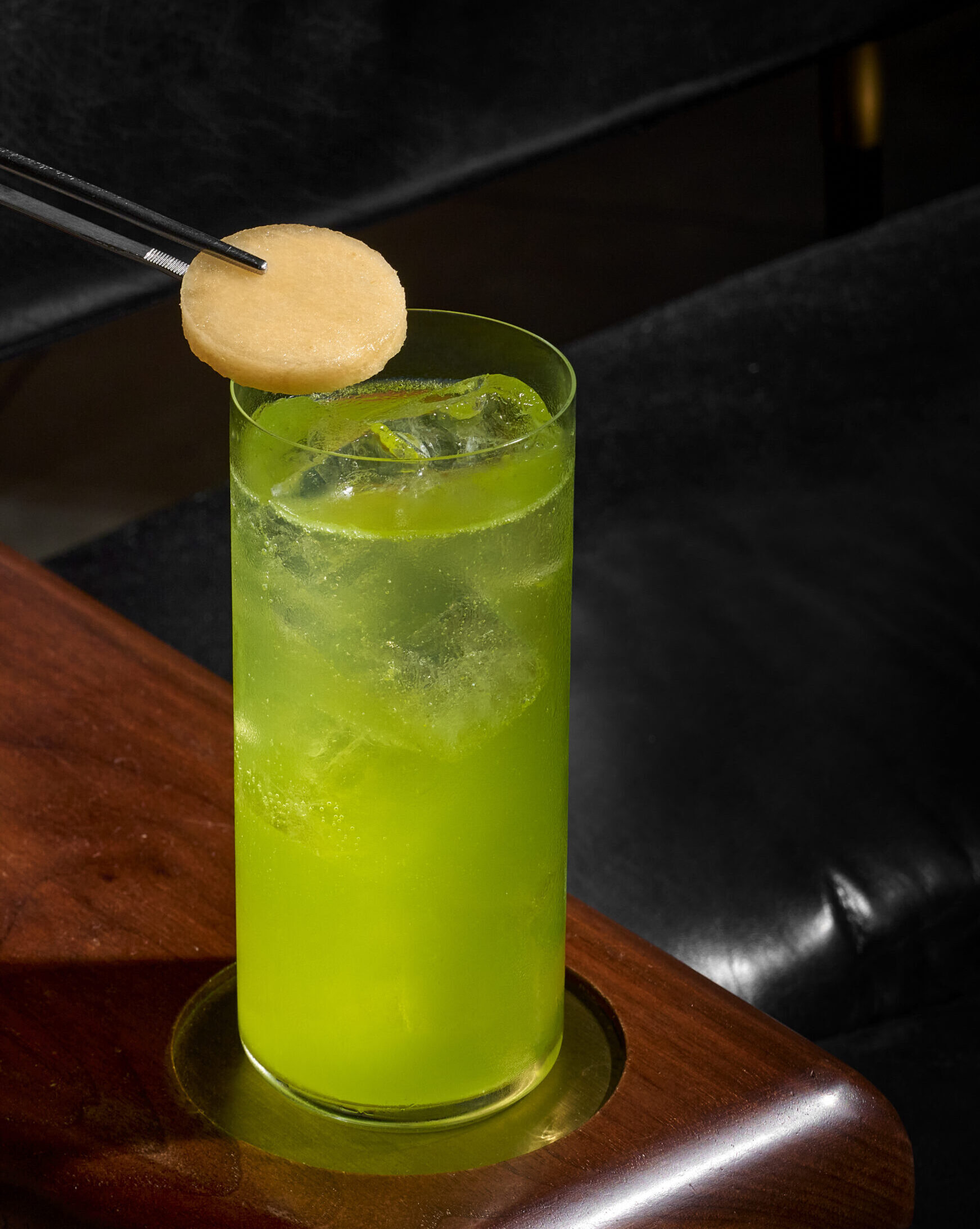 20250716_SC_TWH-Lobby Bar-0854 green coloured drink in a tall glass cup with a person putting a topping in
