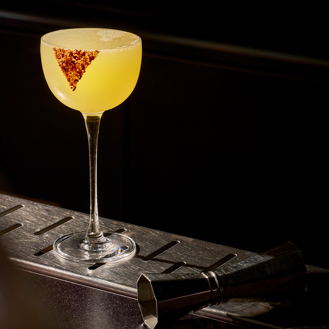 yellow coloured drink in a glass cup against a dark background